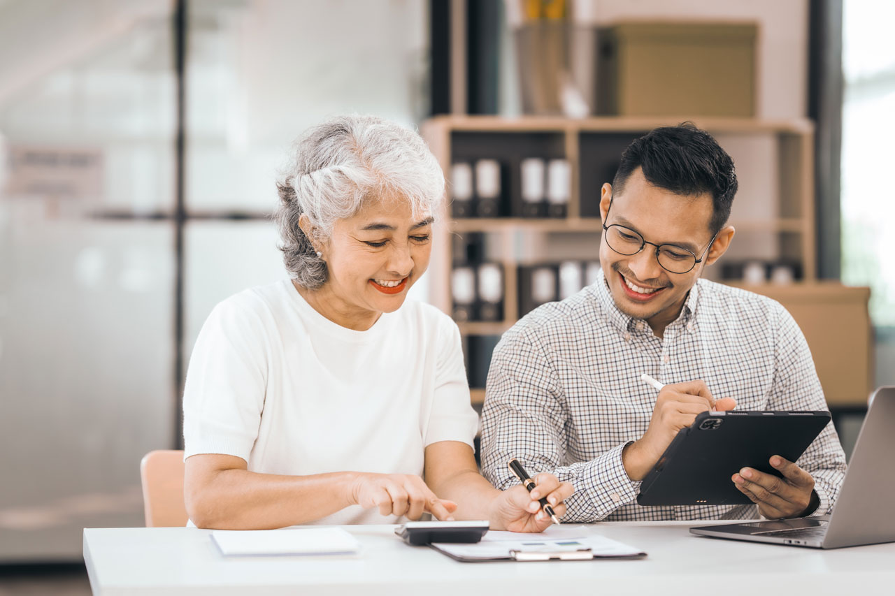 Senior woman calculating finances with an advisor, discussing State Tax Exemptions for retirement income and tax-saving strategies.