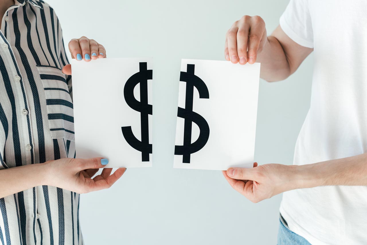 Two people holding separate halves of a dollar sign, symbolizing spousal benefits and shared financial support.